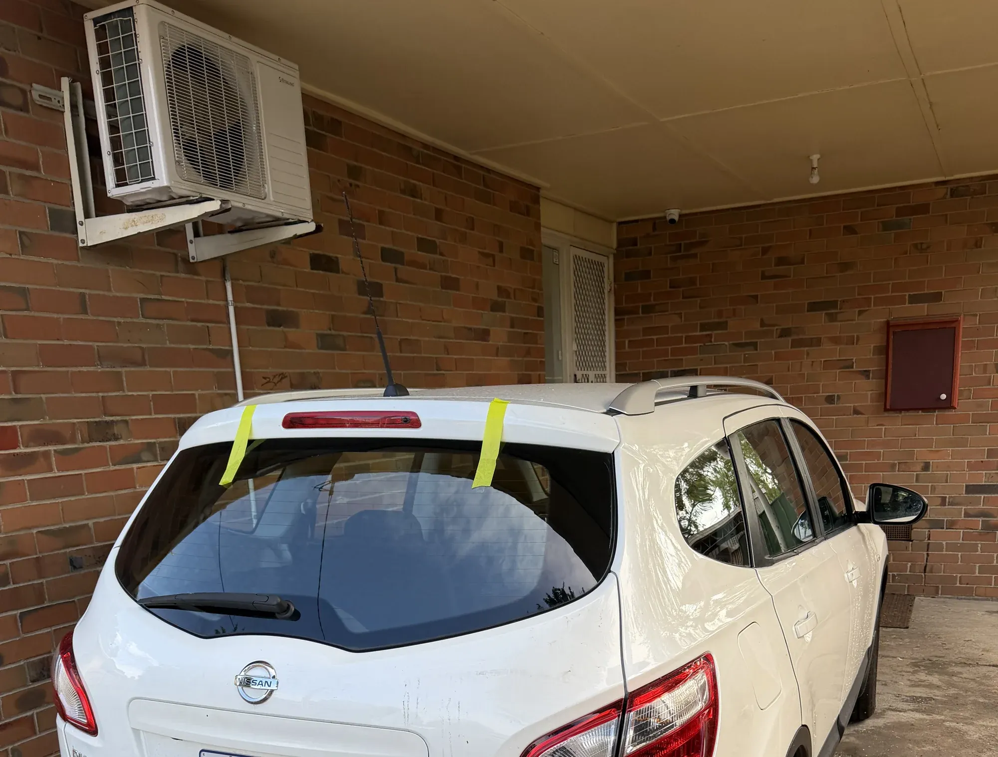 Replacement rear window fitted to a white wagon at a Melbourne home, held with tape while the bond sets