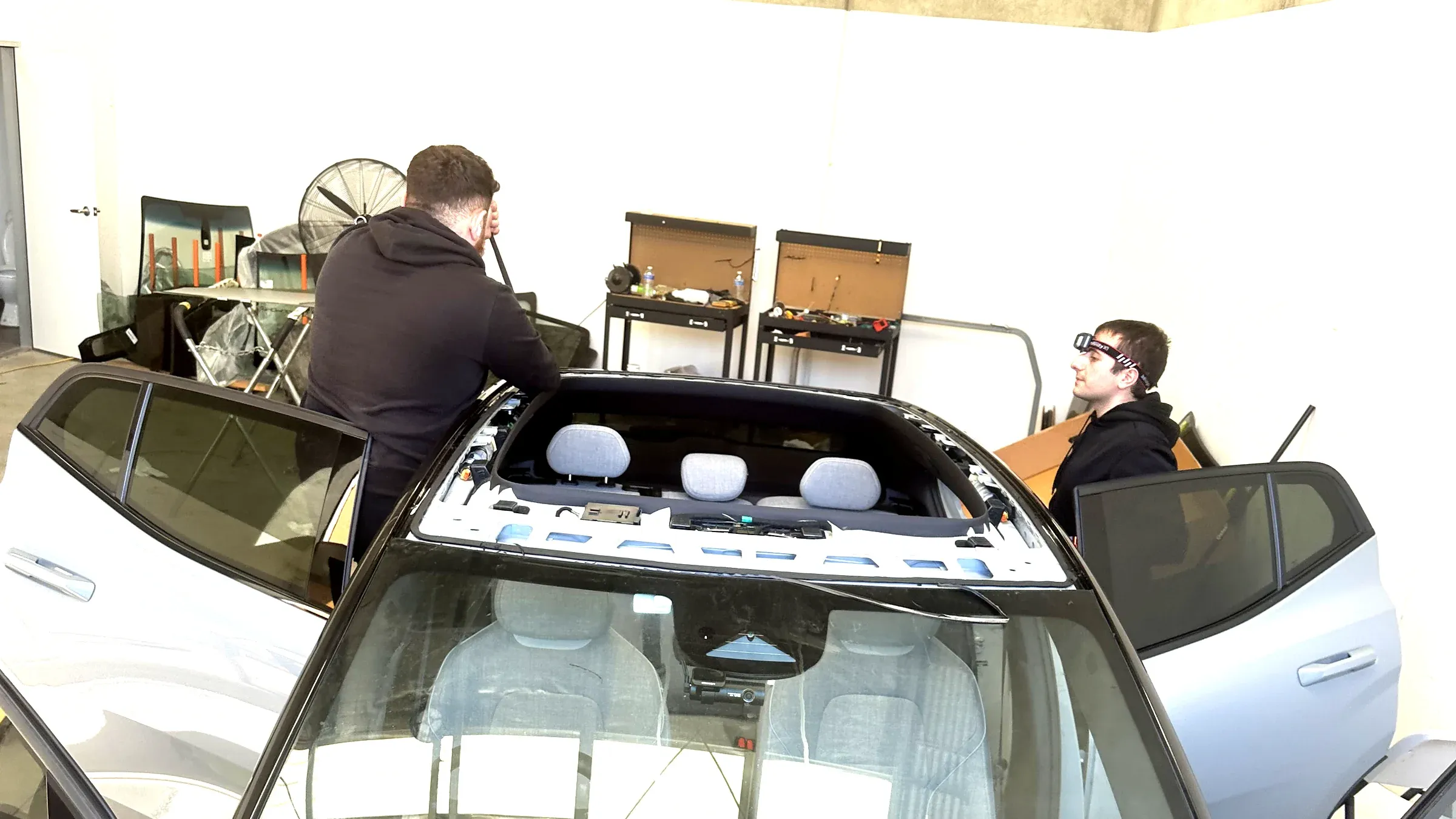 Auto glass technicians replacing vehicle glass on a car in the workshop